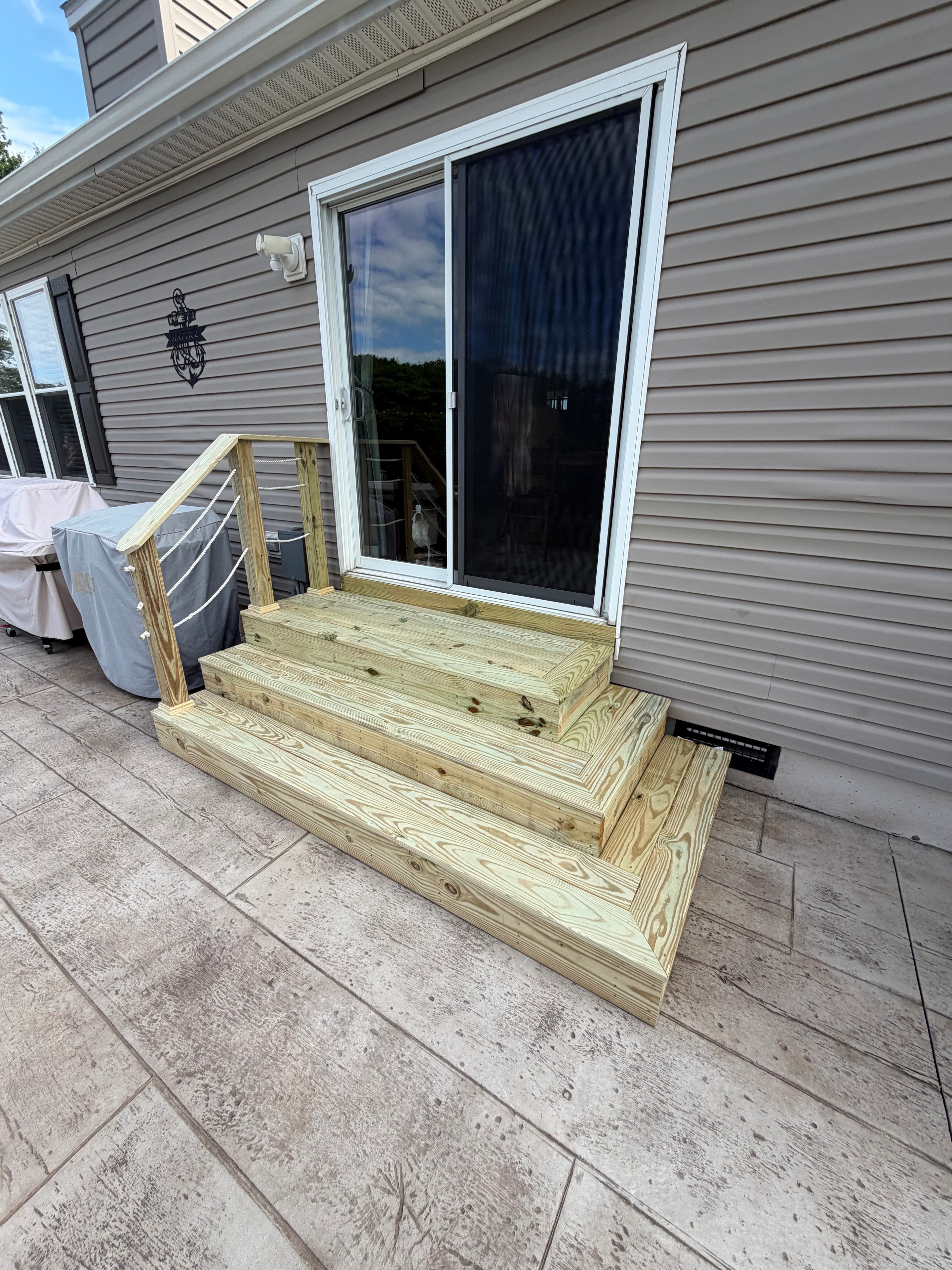 New wood steps with cable railing on stamped concrete patio