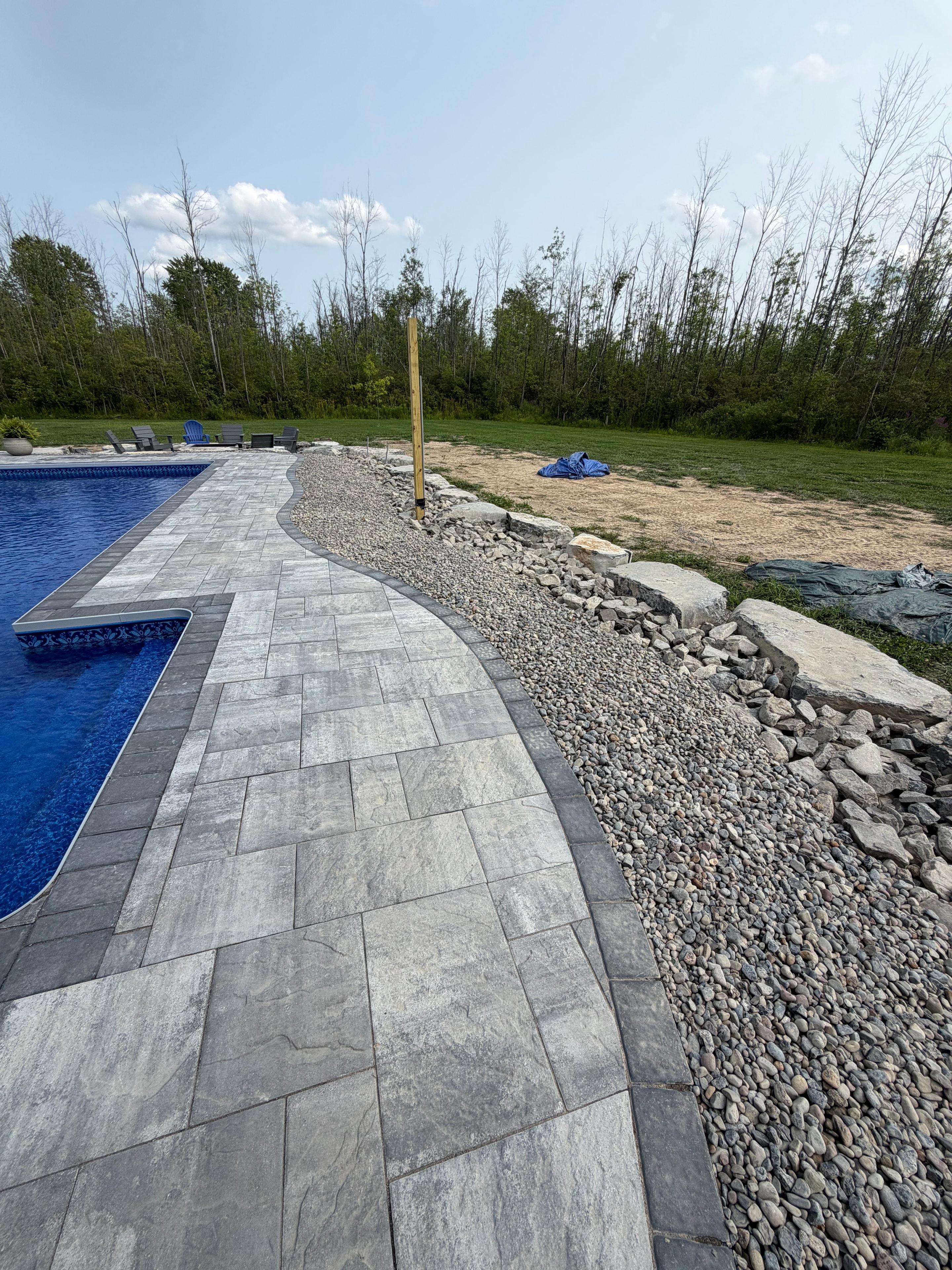 Stone paver pool surround with gravel and boulders