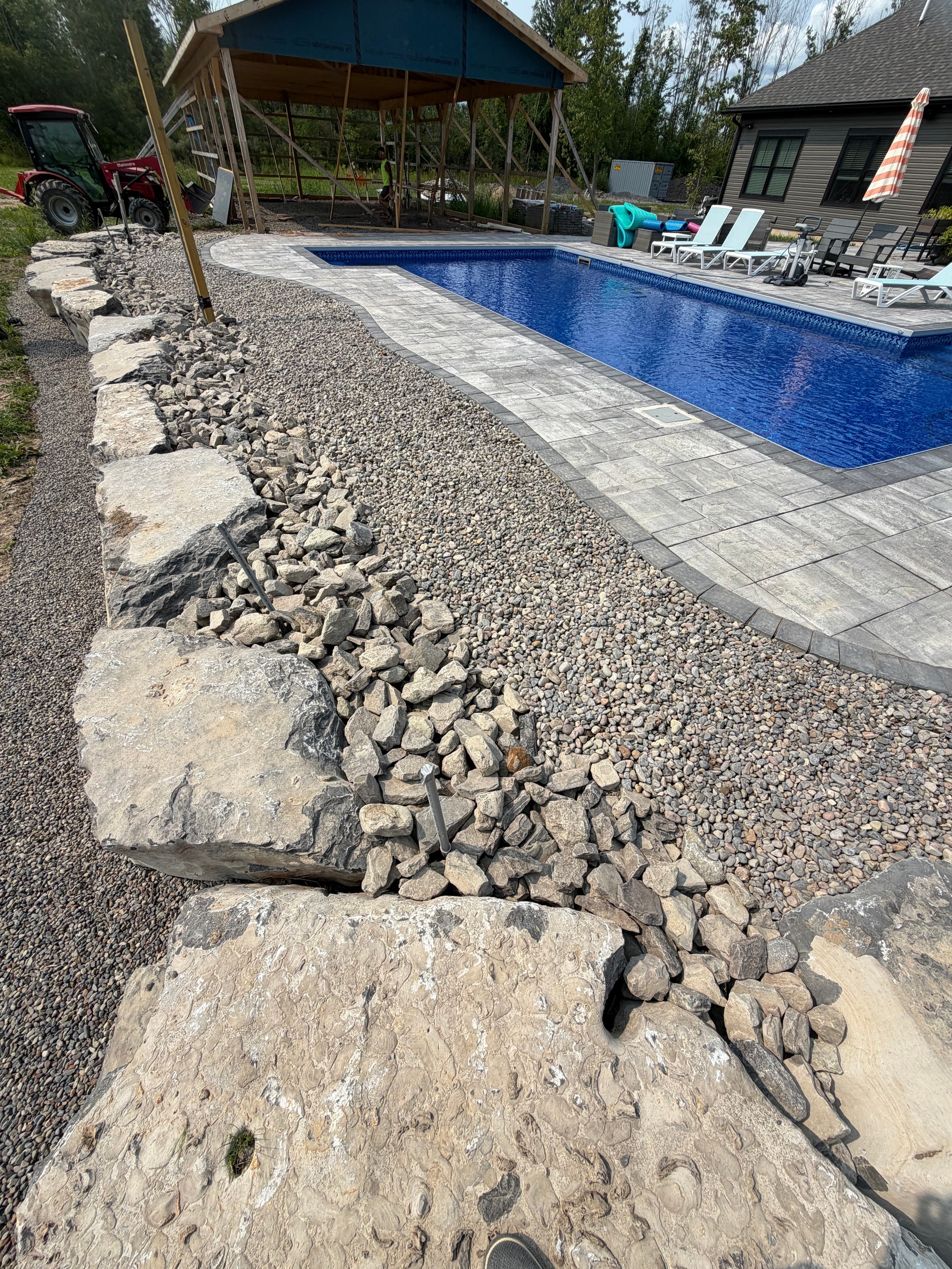 Pool area with boulder retaining wall and paver deck