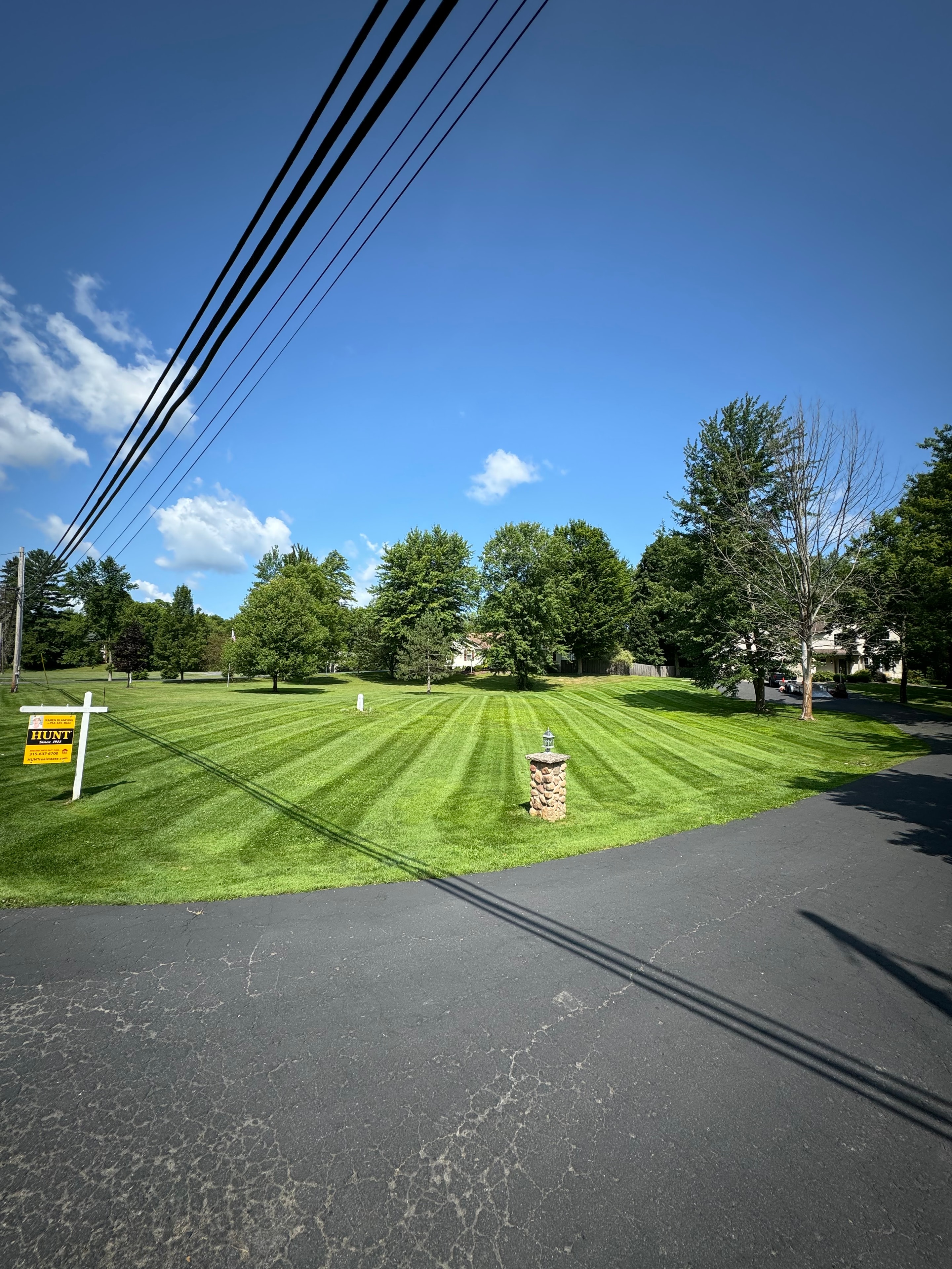 Striped lawn with stone pillar and driveway